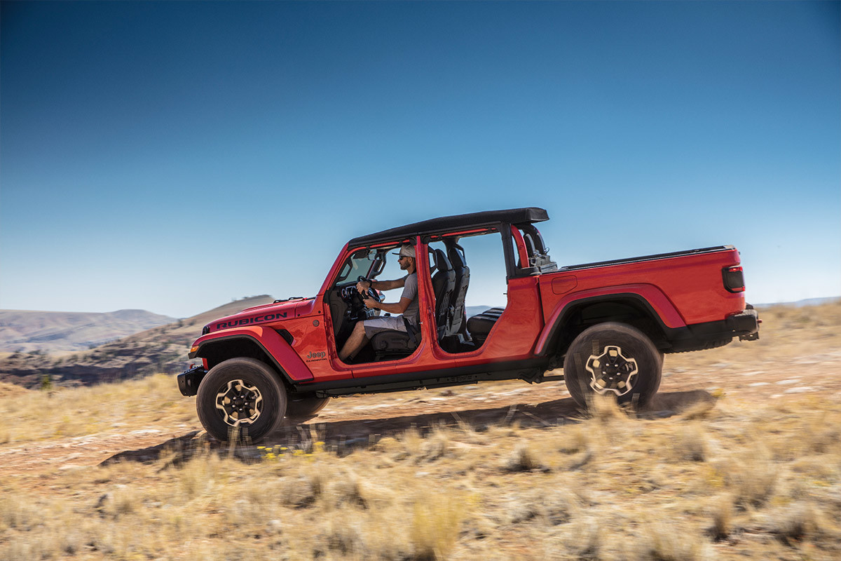 Side view of a red 2022 Jeep Gladiator parked in a field.