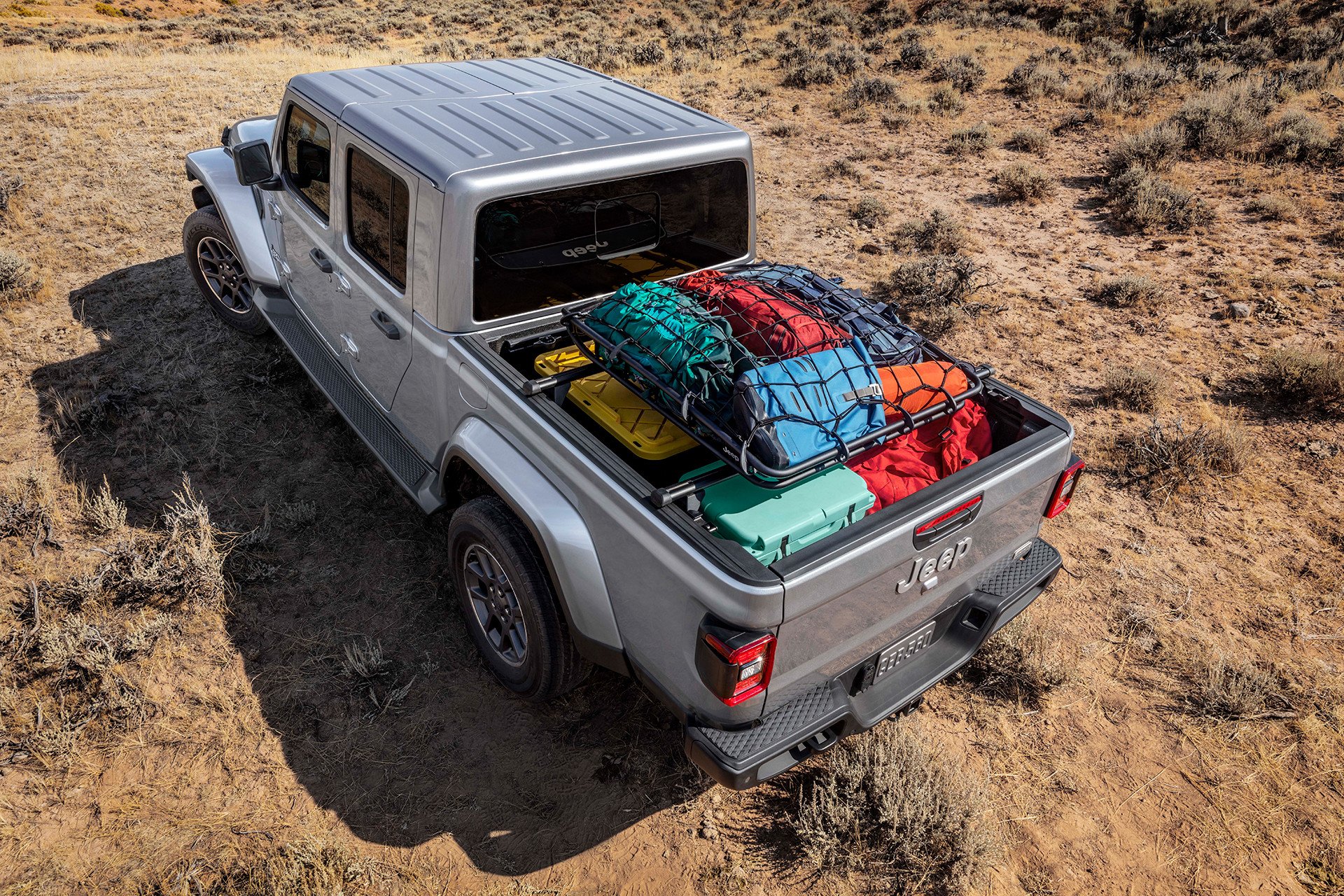 Top down view of a light grey 2022 Jeep gladiator with the truck bed filled with camping supplies.