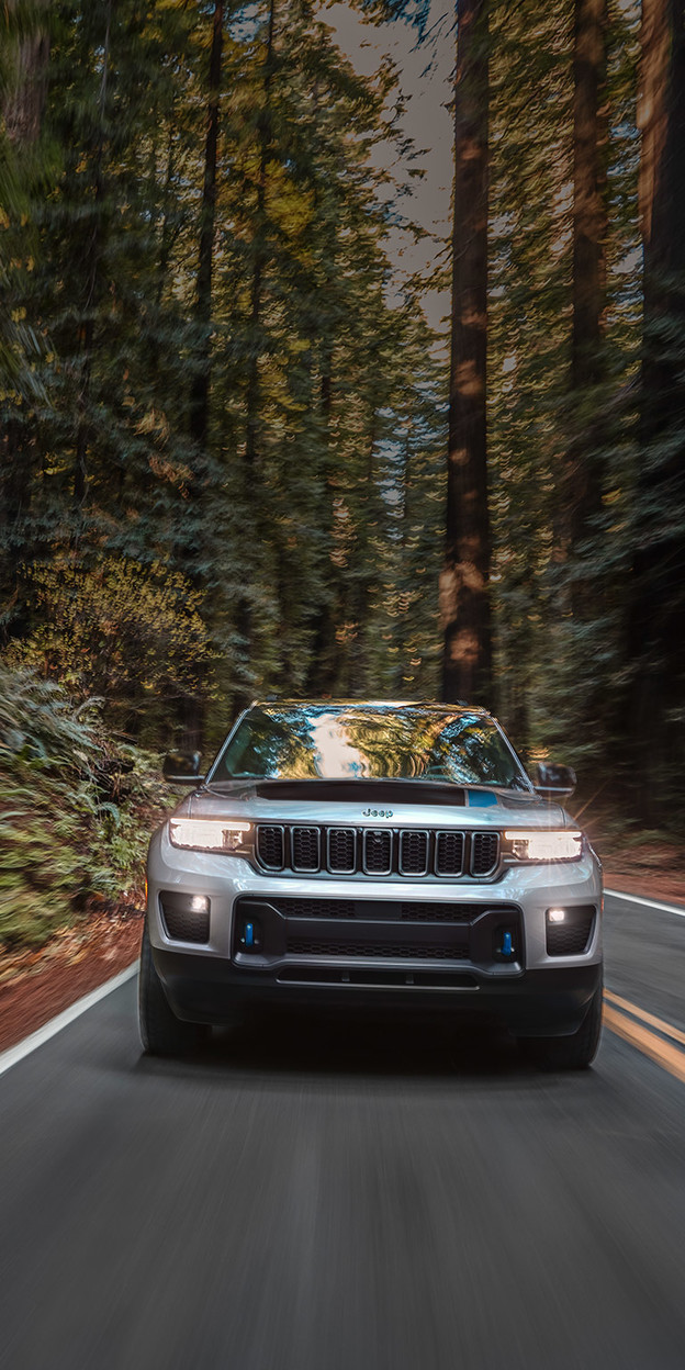 Jeep Grand Cherokee 2022 gris roulant sur une route pavée dans une forêt