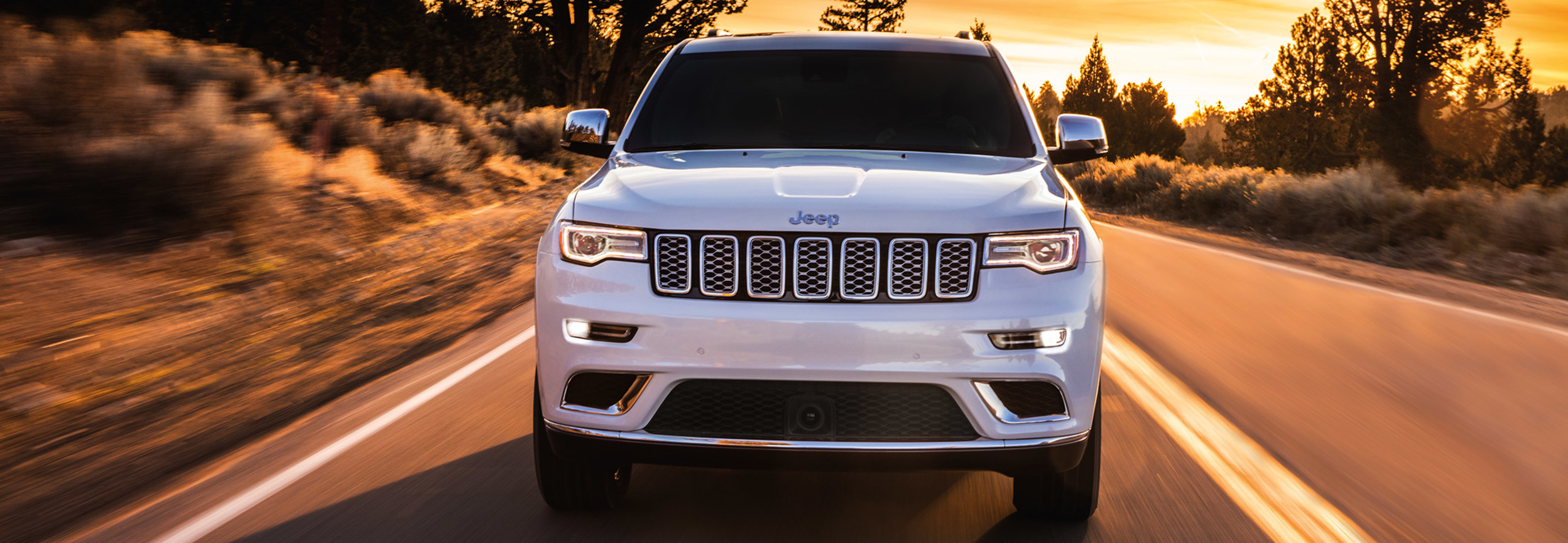 Front view of a Jeep Grand Cherokee driving down a road