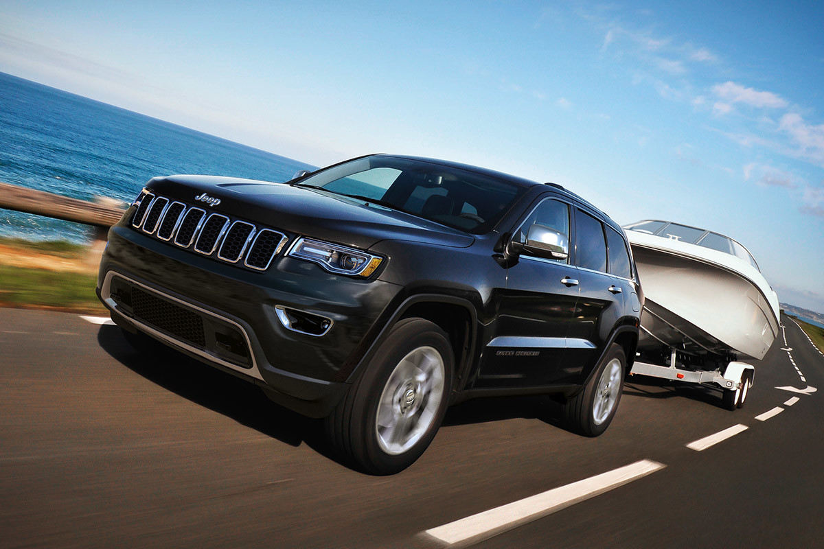 Black 2020 Jeep Grand Cherokee towing a large white boat.