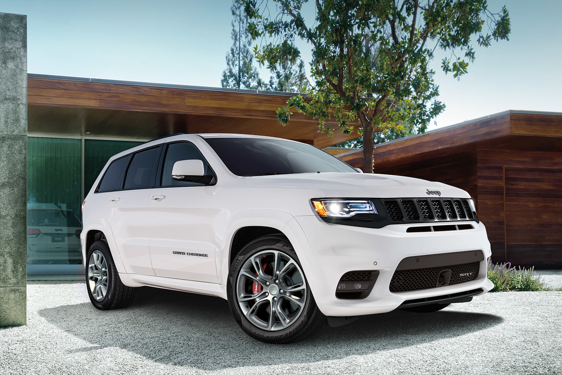Vue avant d’un Jeep Grand Cherokee 2020 blanc stationné dans une entrée devant une maison