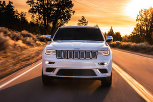 Jeep Grand Cherokee 2021 blanc roulant sur une route bordée d’arbres et d’arbustes