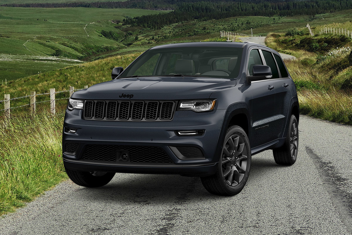 Black Jeep Grand Cherokee parked on a road with lush green fields in the background.