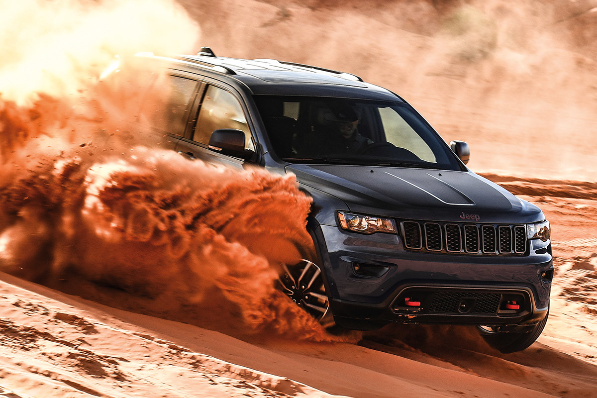 Jeep Grand Cherokee 2021 gris métallisé faisant virevolter du sable alors qu’il roule sur un banc de sable