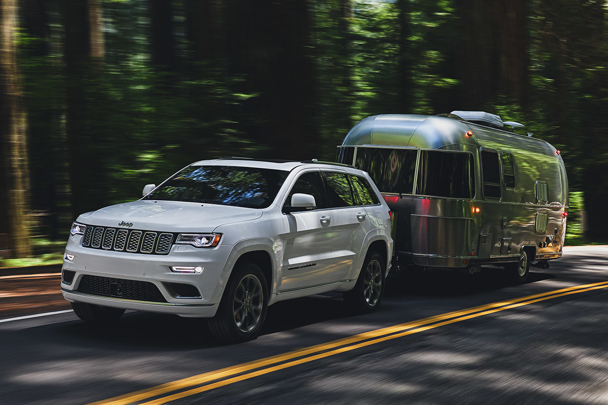 2021 Jeep Grand Cherokee in white towing a silver trailer.