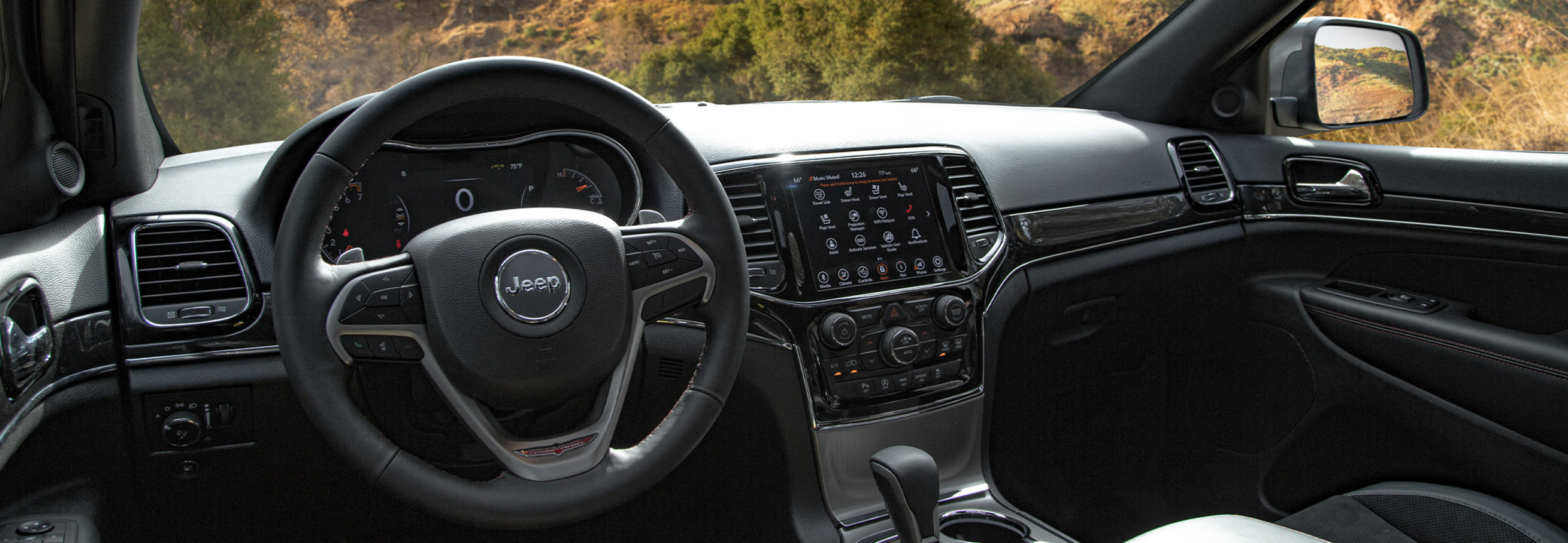 Forward-facing view of the Grand Cherokee WK interior overlooking a rugged, rocky outdoors setting.