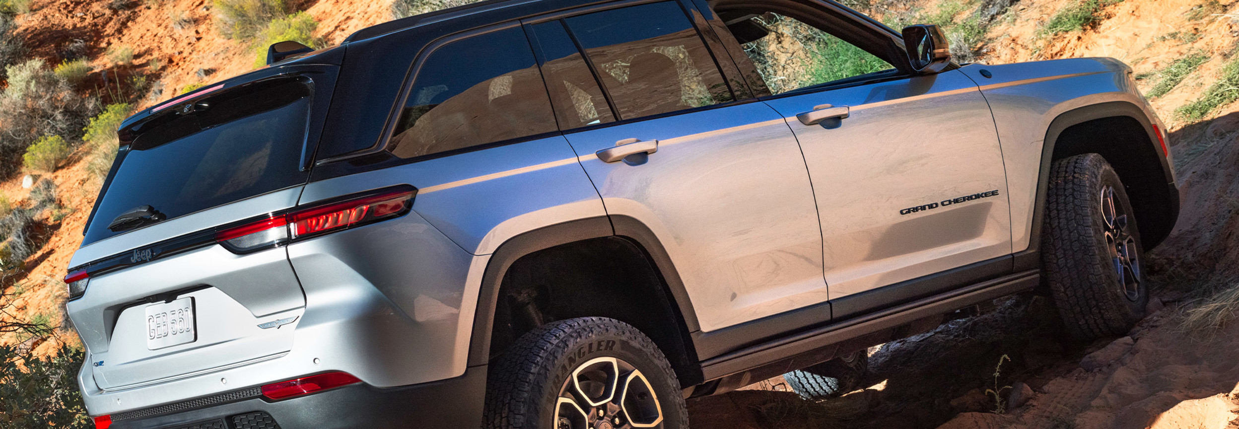 Un tout nouveau Jeep Grand Cherokee 4xe 2022 argent roulant dans une montée.