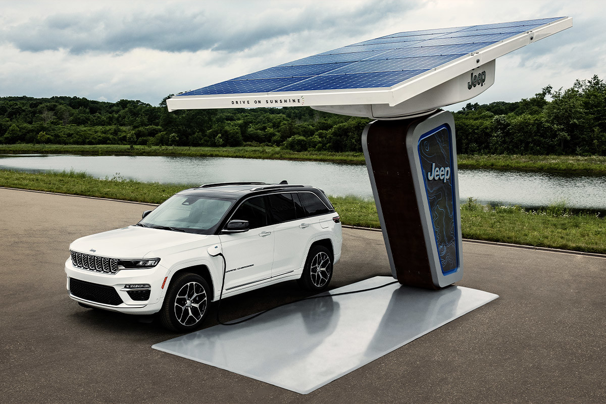Le tout nouveau Jeep Grand Cherokee 2022 montré en blanc, garé à une borne de recharge dans le désert.