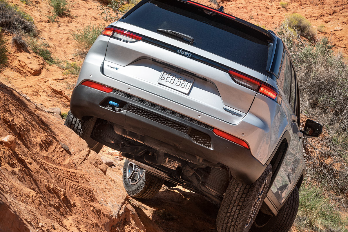 L’arrière d’un tout nouveau Jeep Grand Cherokee 4xe 2022 argent roulant descendant une colline rocheuse.