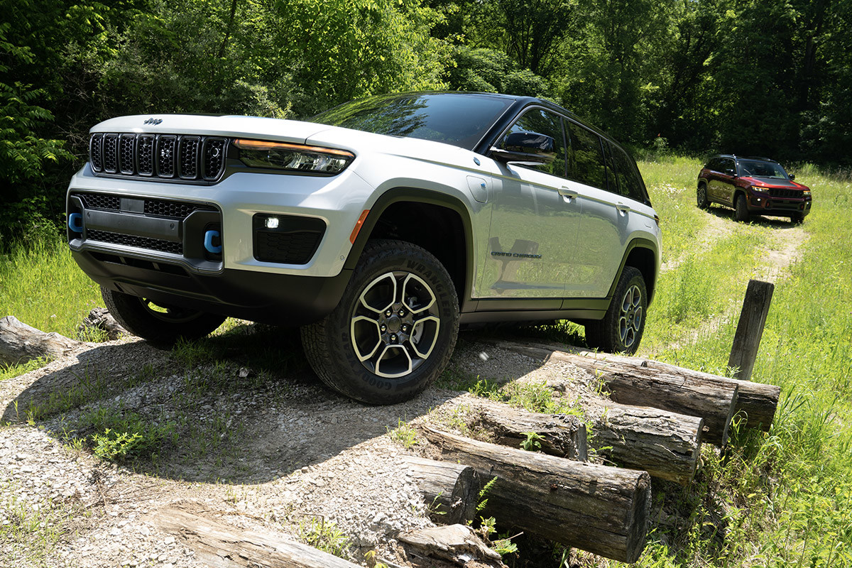A white All-New 2022 Jeep Grand Cherokee 4xe driving over logs.