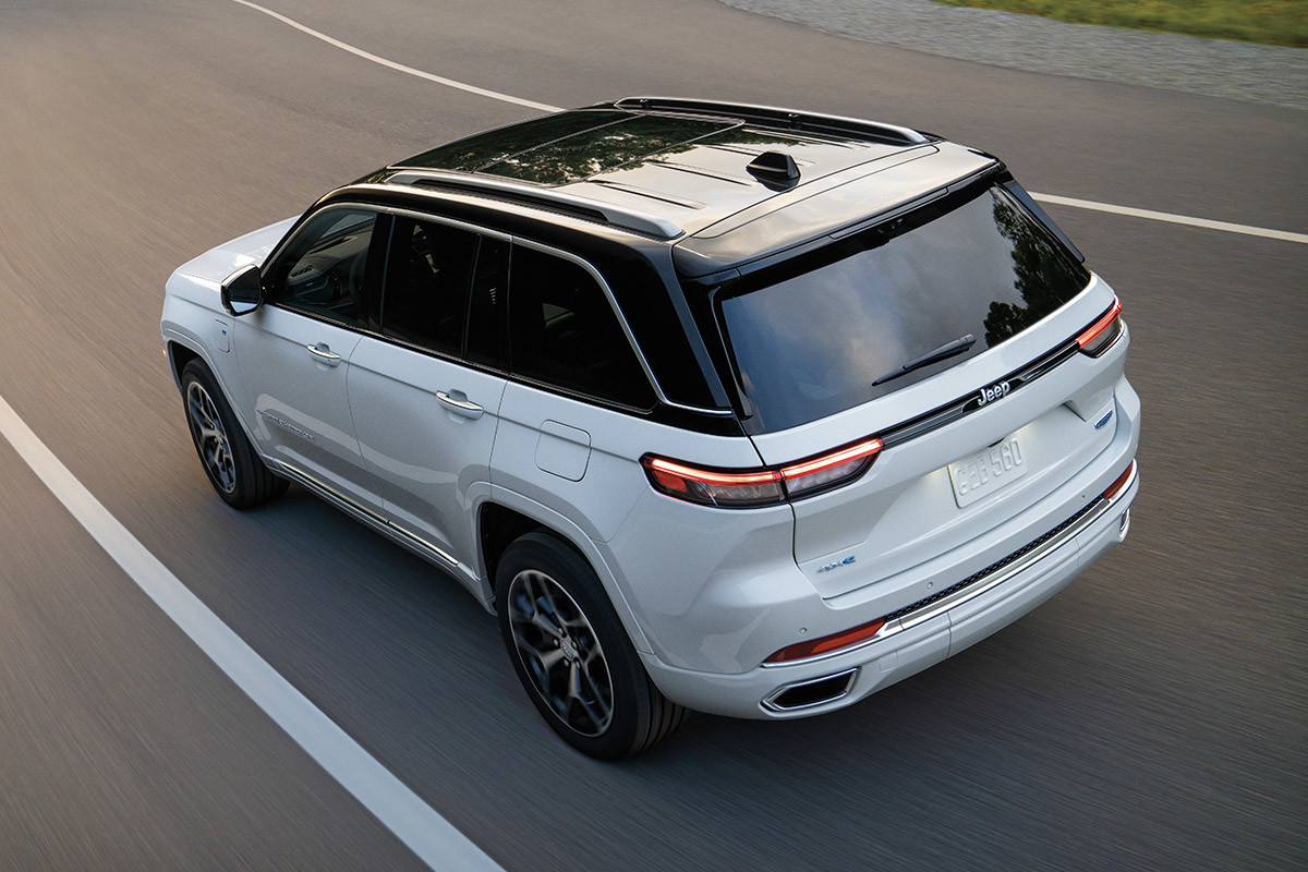 A white All-New 2022 Jeep Grand Cherokee 4xe being driven down a highway.