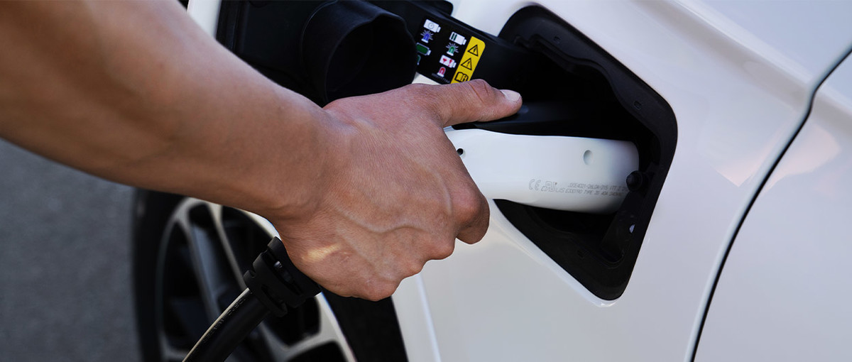 Une image de la main d’une personne rechargeant un Jeep Grand Cherokee 4xe 2022 blanc.