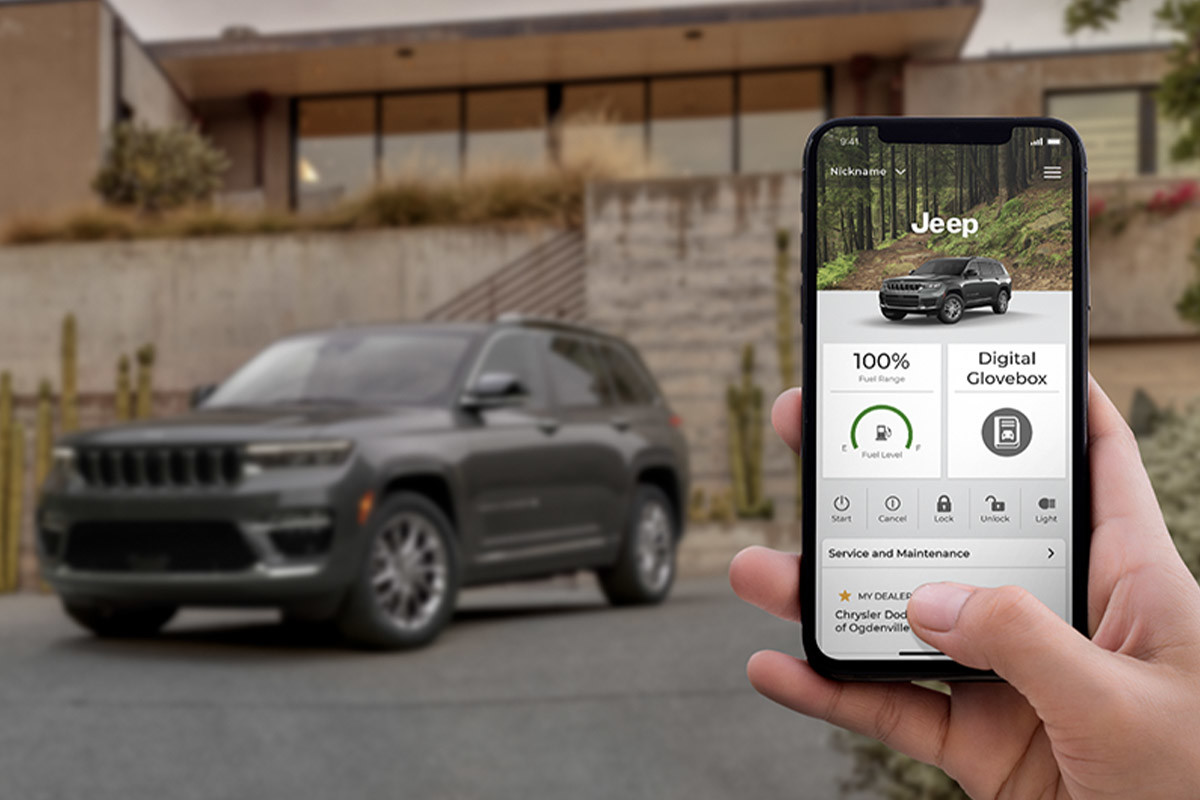 Gros plan d’un téléphone avec les services pour véhicules connectés et un tout nouveau Jeep Grand Cherokee 4xe en arrière-plan.