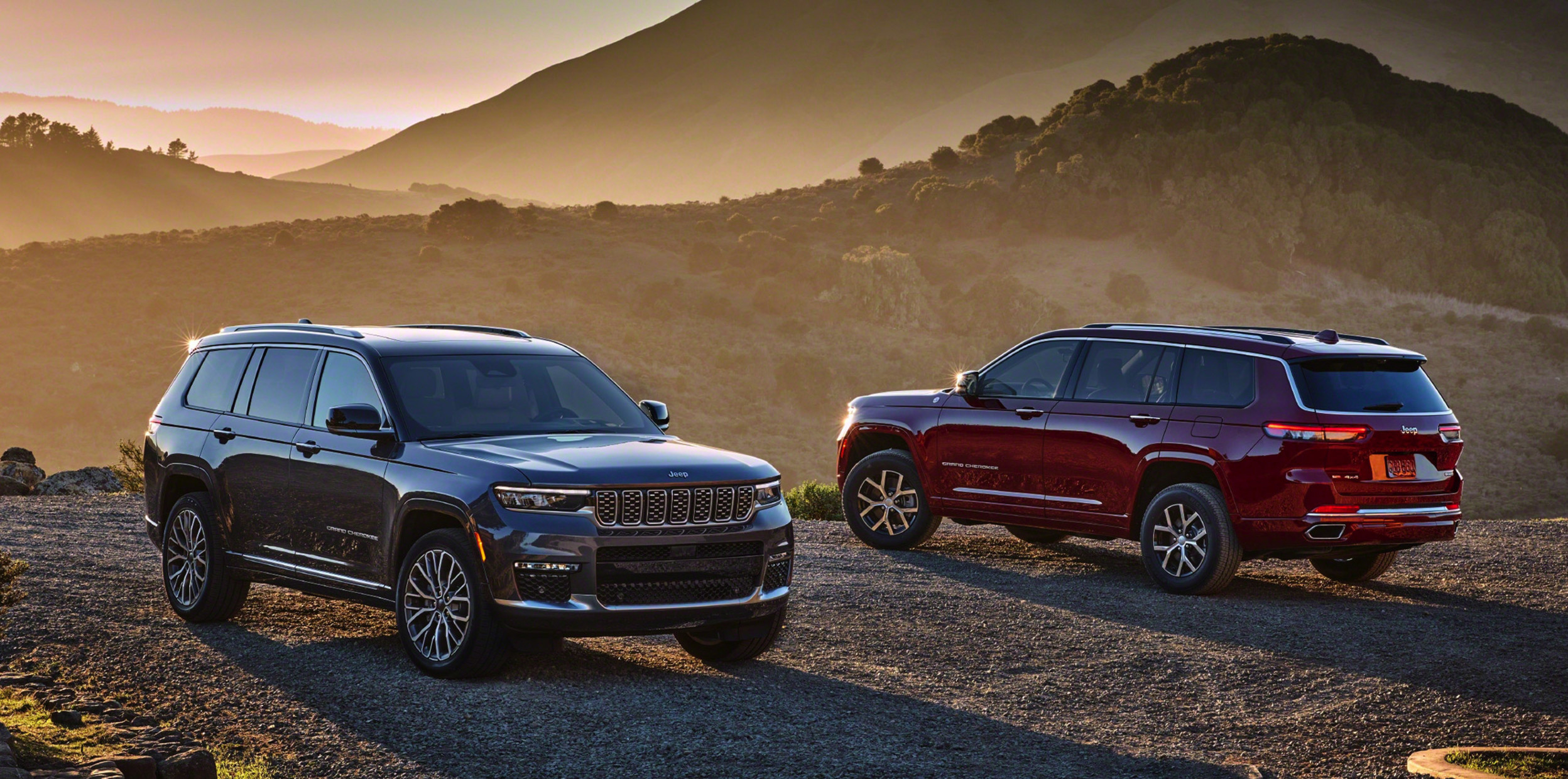Vue d’un tout nouveau Grand Cherokee L 2021 gris stationné sur une route de gravier dans le désert. Un deuxième Grand Cherokee L est stationné en arrière-plan.
