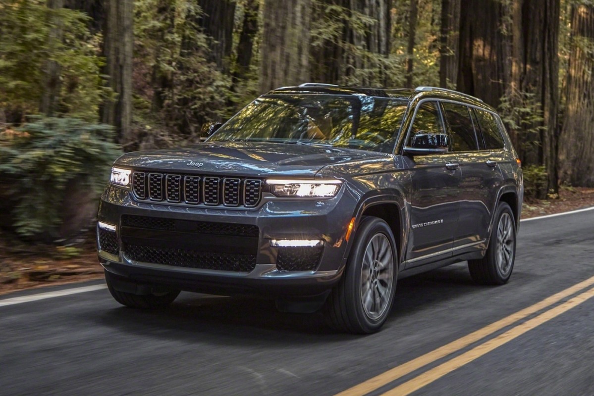 Un Jeep Grand Cherokee L 2021 roulant sur l'autoroute à côté d'une forêt.