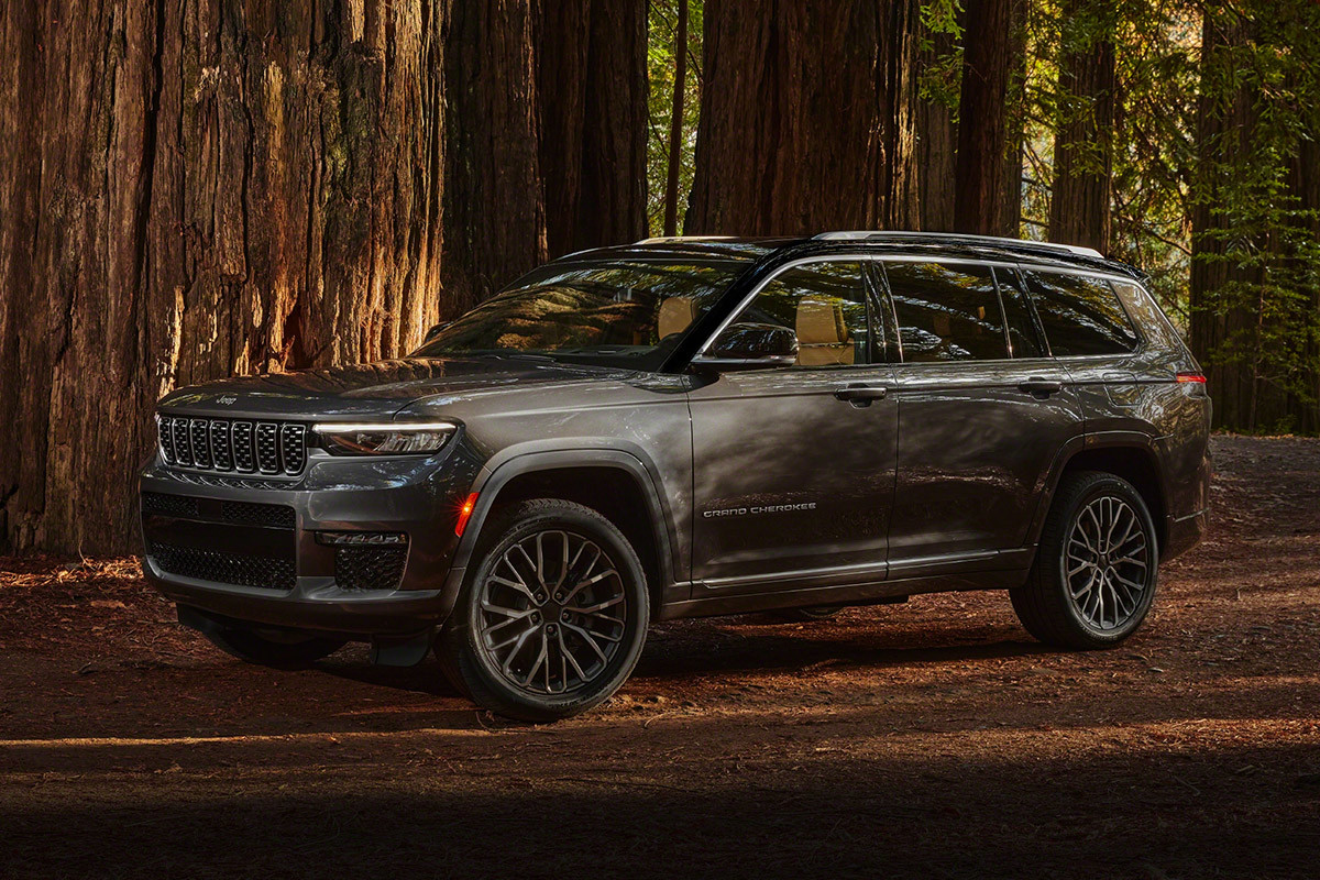 Vue latérale d’un tout nouveau Grand Cherokee L 2021 gris stationné sur un sentier forestier.