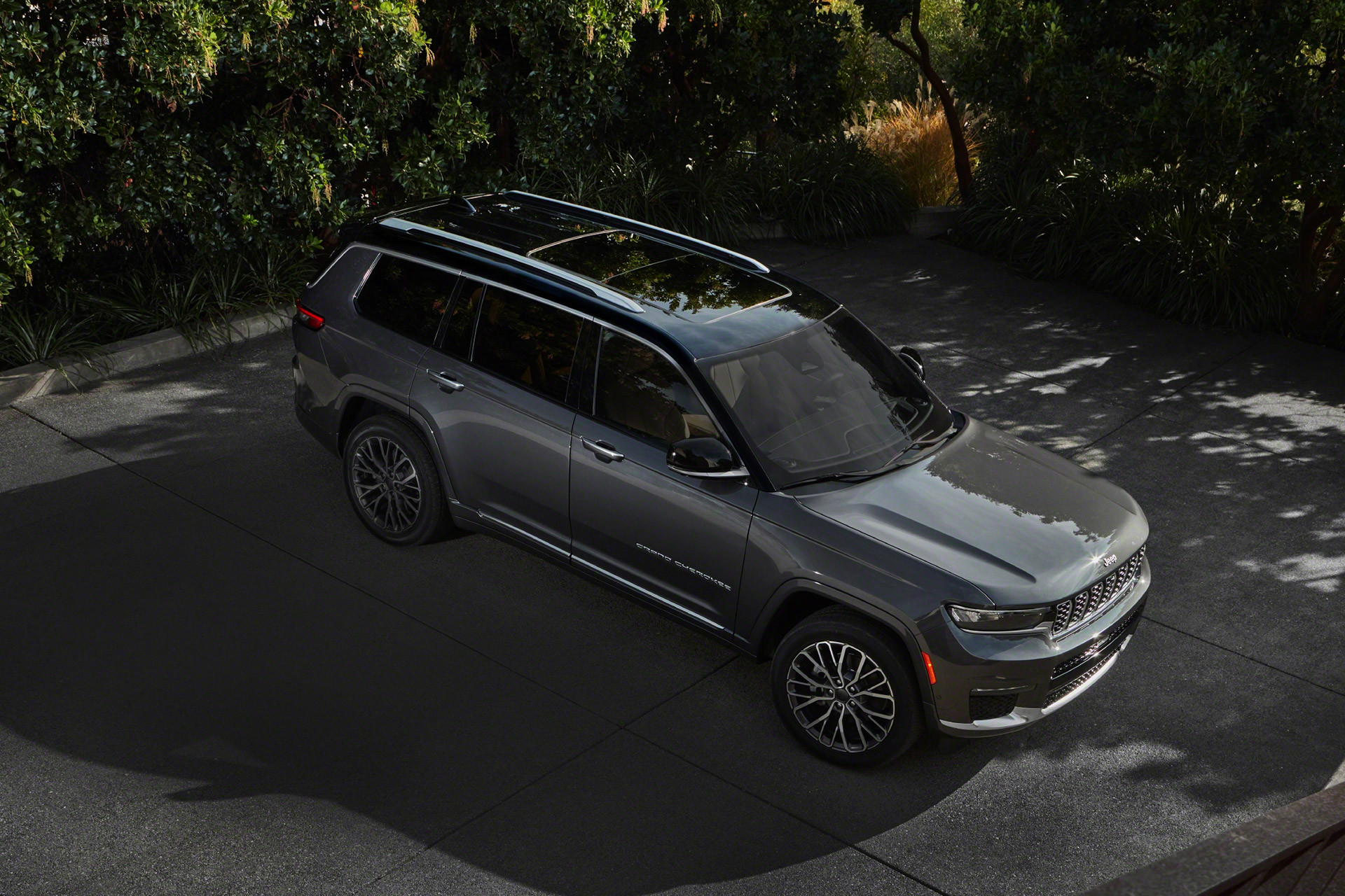 Vue en plongée d’un tout nouveau Grand Cherokee L 2021 gris garé dans une aire de stationnement.