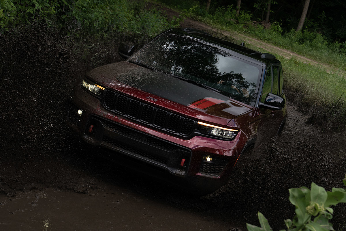 Un Jeep Grand Cherokee rouge roulant dans la boue.