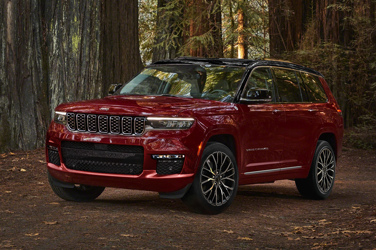 Un Jeep Grand Cherokee 2022 rouge, garée dans les bois, entourée de grands arbres.