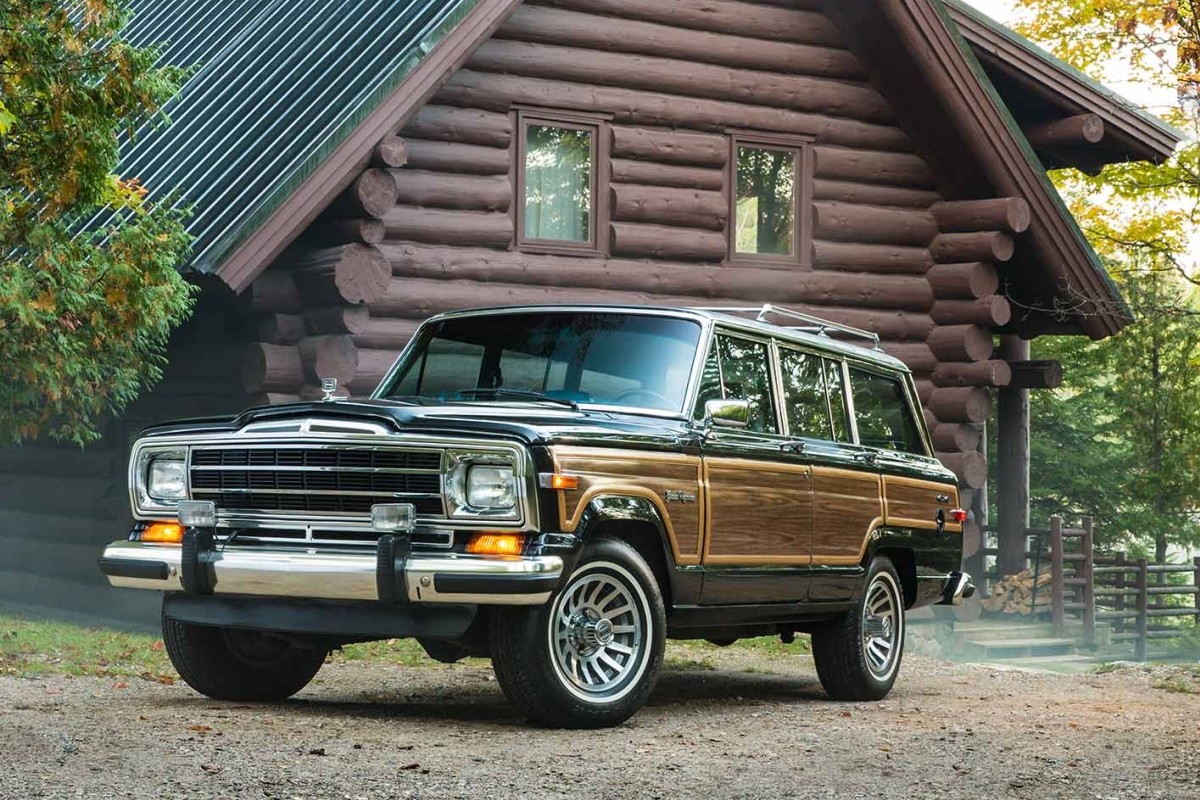 Grand Wagoneer stationné devant une cabane en rondin dans les bois.