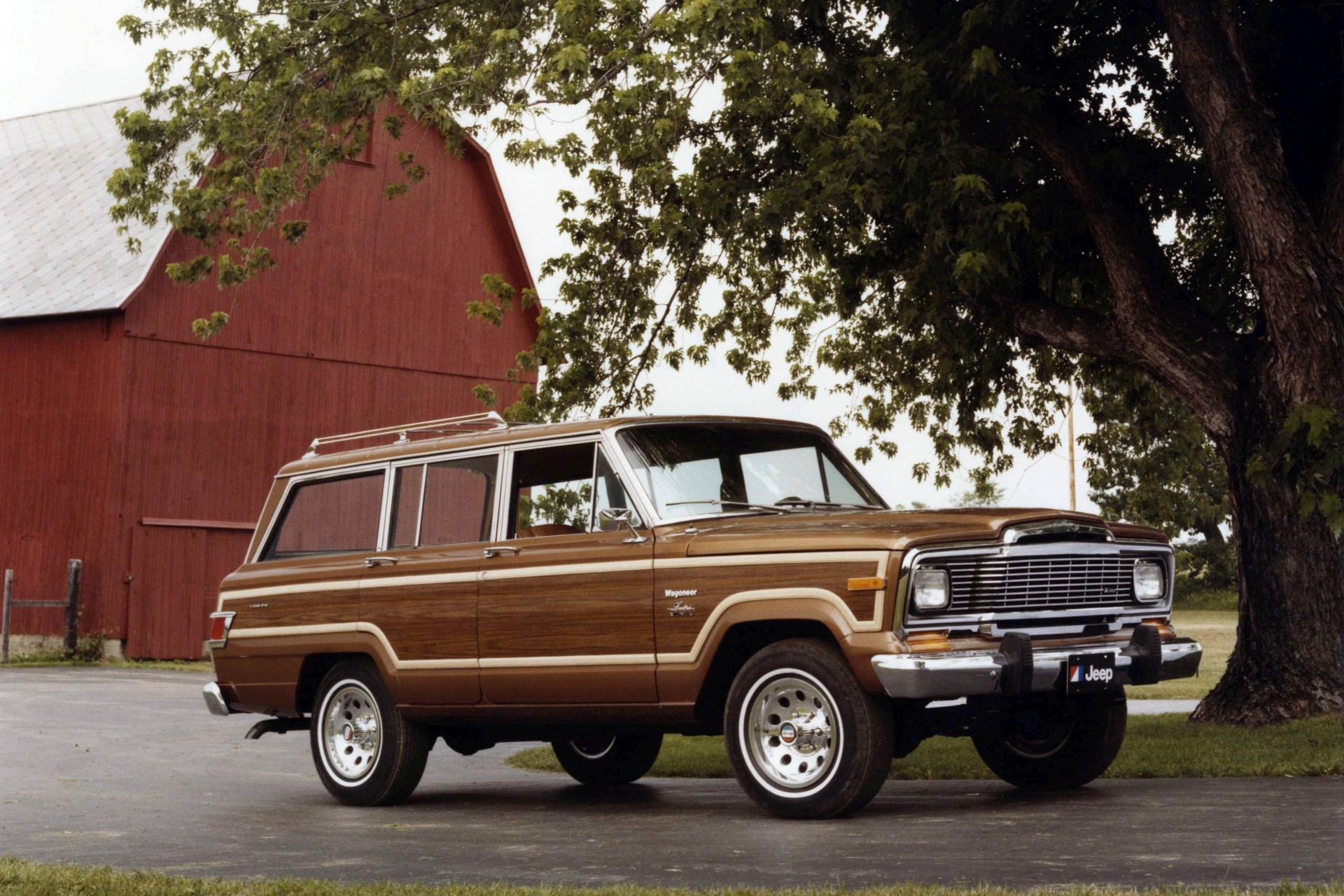 1970’s Jeep Wagoneer parked in front of a red barn.
