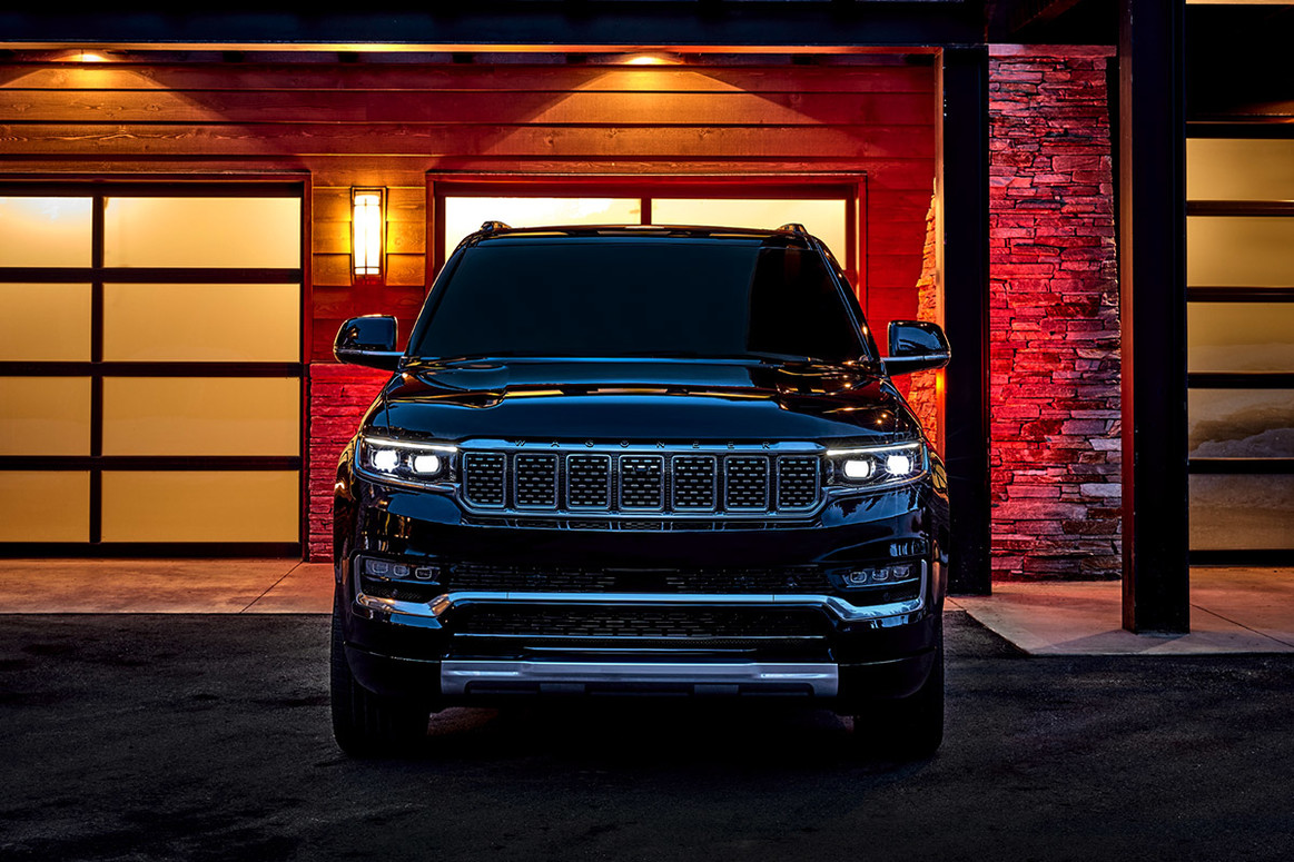 A black All-New 2022 Grand Wagoneer, parked in front of the garage of a house.