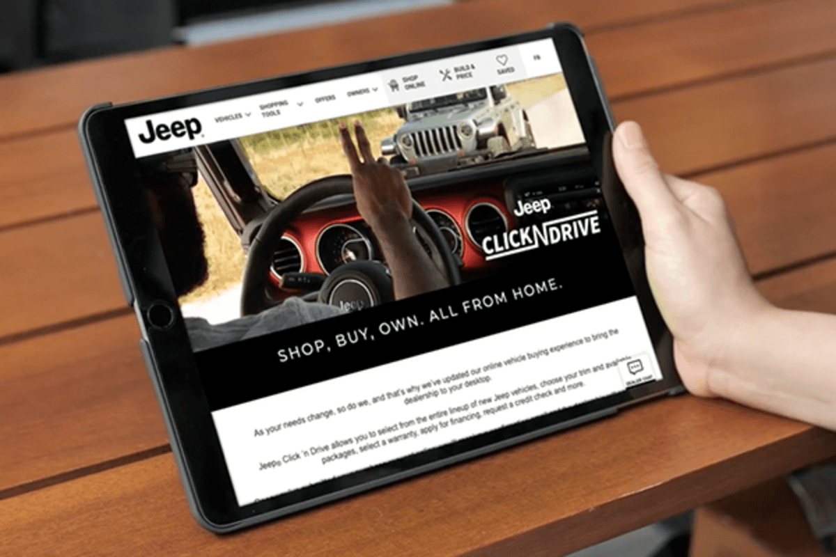 BRING THE DEALERSHIP TO YOUR DEVICES A tablet showing the Jeep Click N Drive webpage on its screen.