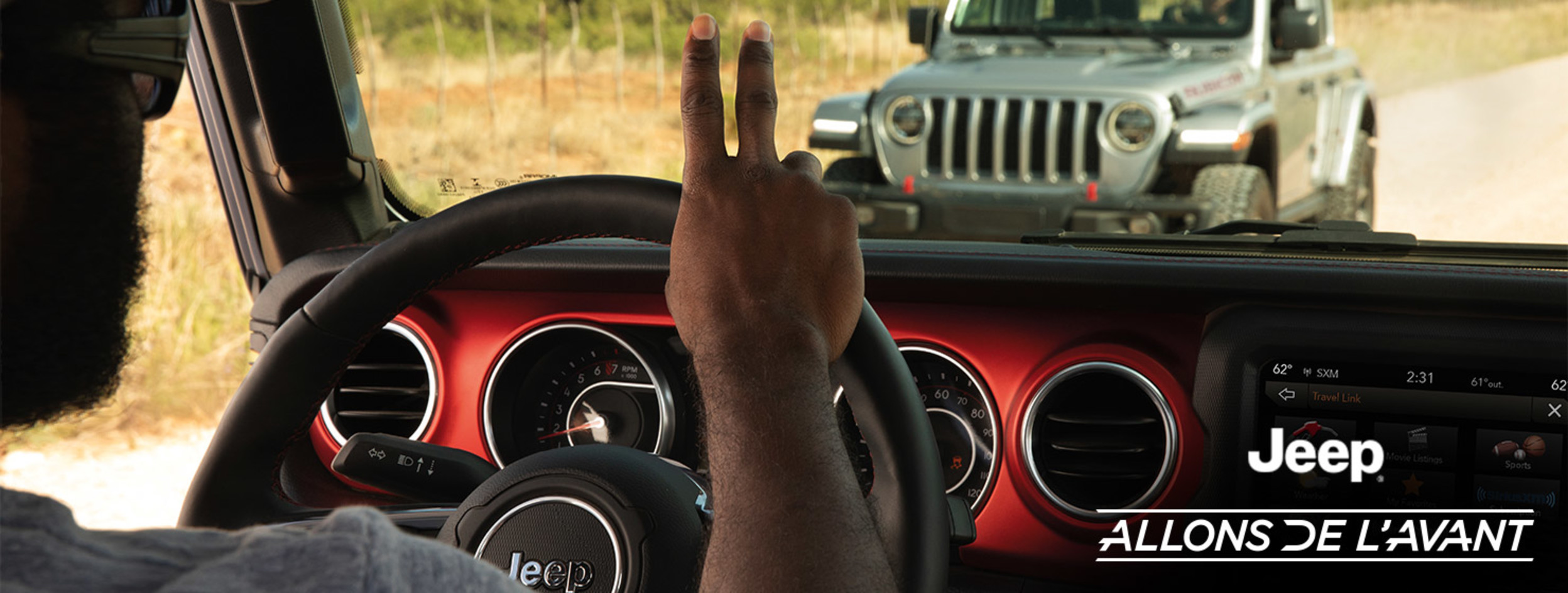 Programme Allez de l’avant avec Jeep® Une personne dans un Jeep® Wrangler roulant sur une route de terre salue une autre personne qu’elle croise dans un Jeep® Wrangler gris.