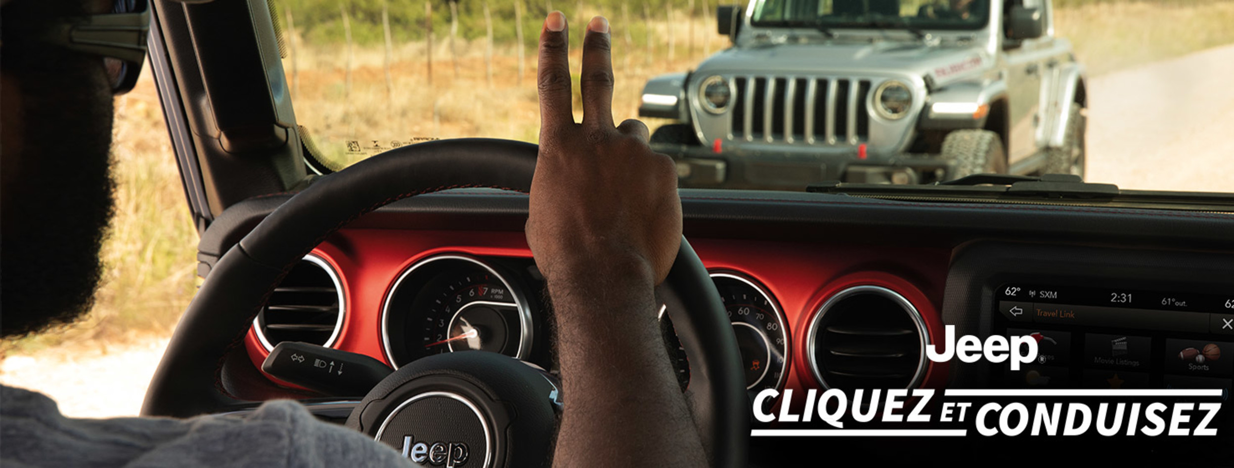 Programme Allez de l’avant avec Jeep® Une personne dans un Jeep® Wrangler roulant sur une route de terre salue une autre personne qu’elle croise dans un Jeep® Wrangler gris.