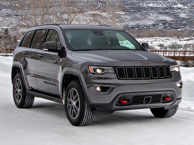 Grand Cherokee Trailhawk in Granite Crystal Metallic parked on snowy country road near bridge, mountains behind.