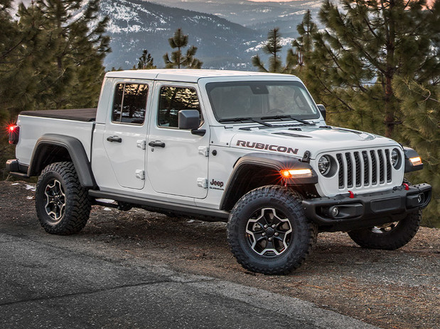Gladiator Rubicon in Bright White, parked on the side of a paved road surrounded by trees in the snow covered woods