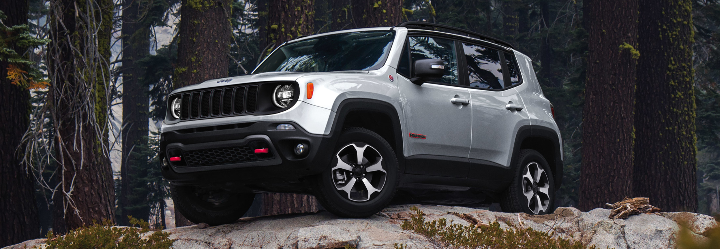 Un Jeep Renegade argenté stationné au milieu d’une forêt