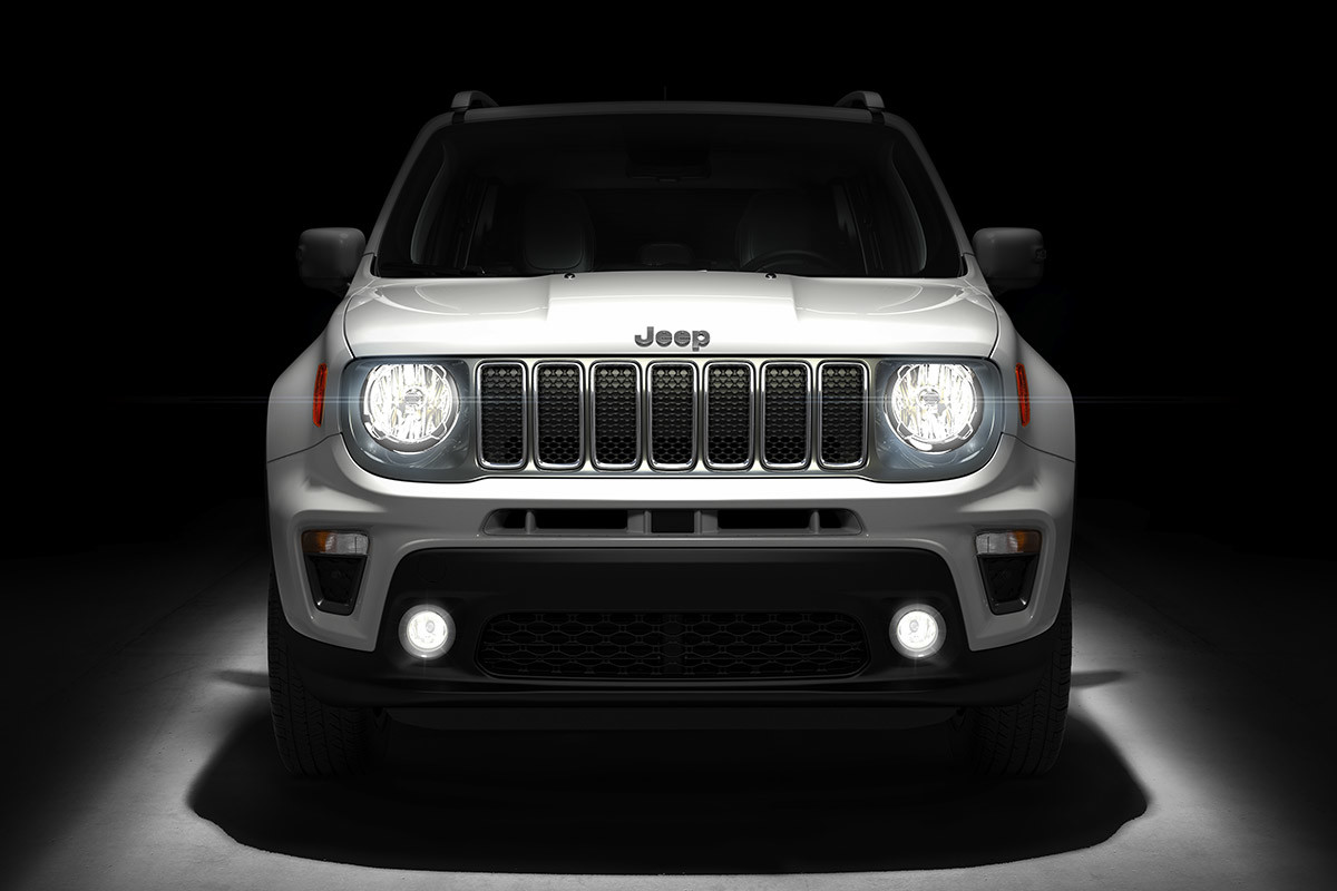 Front view of 2020 Jeep Renegade in a darkened studio highlighting its headlights