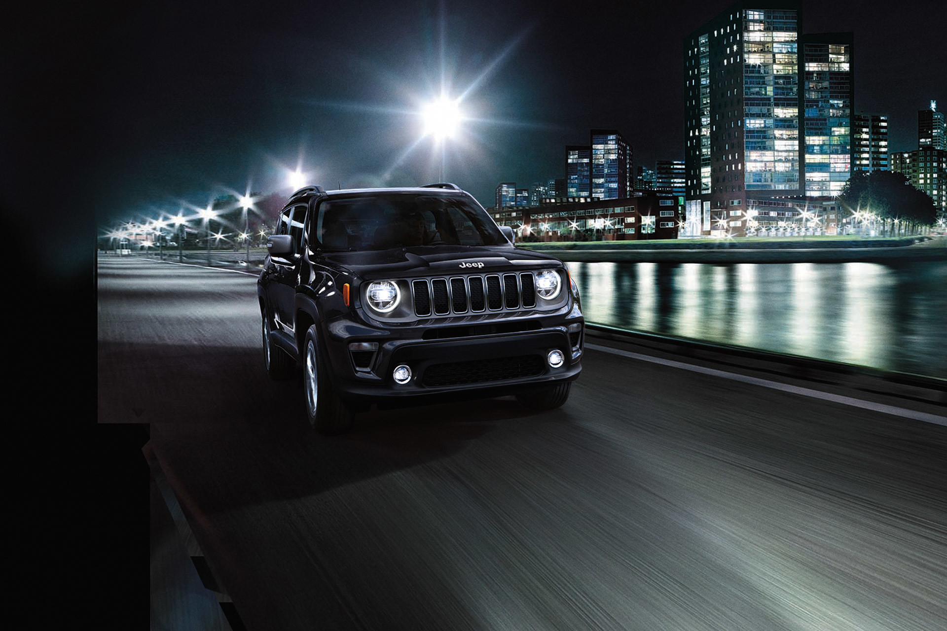 Black 2020 Jeep Renegade being driven on a road beside a river at night