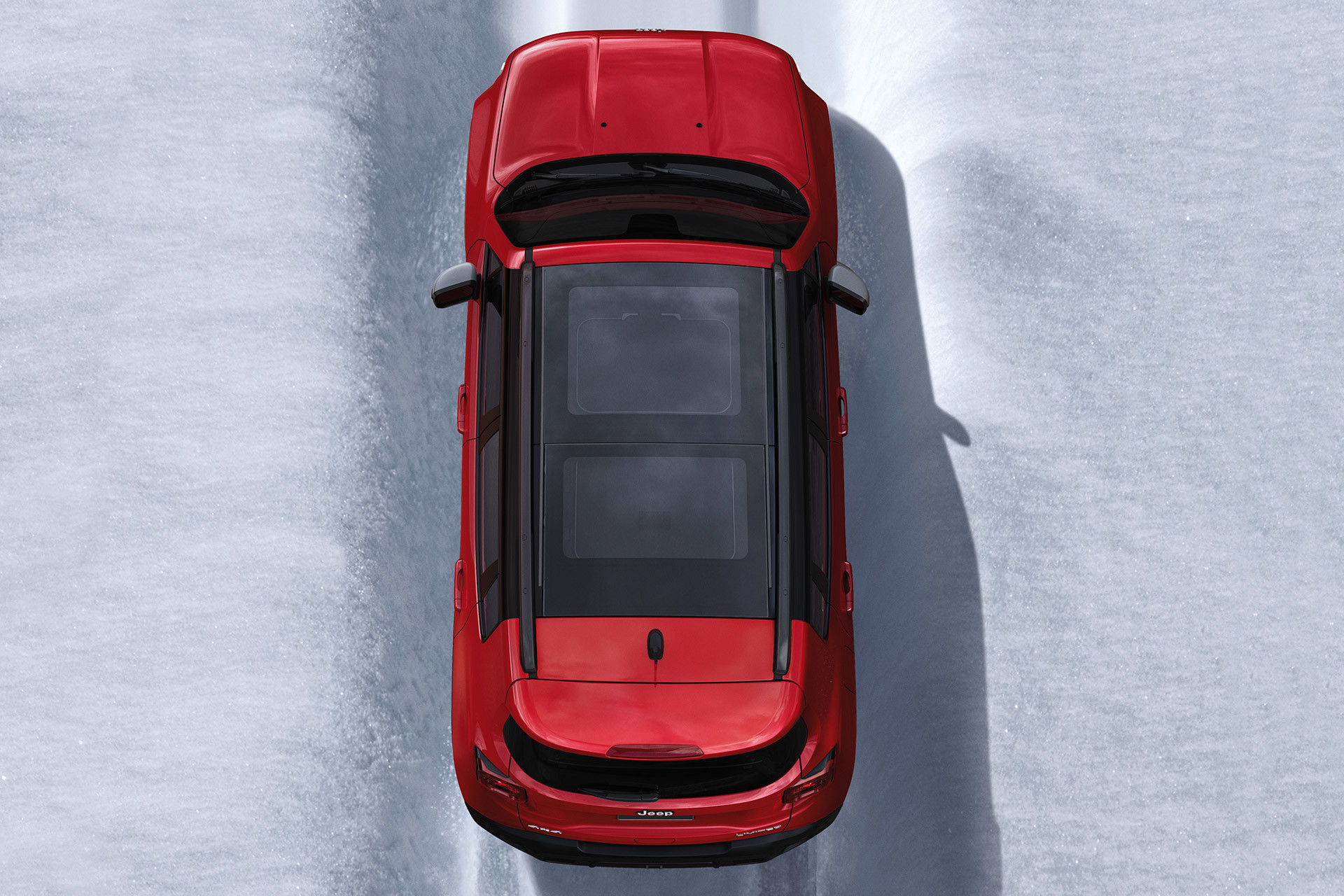 Bird eye view of red 2020 Jeep Renegade being driven on snow