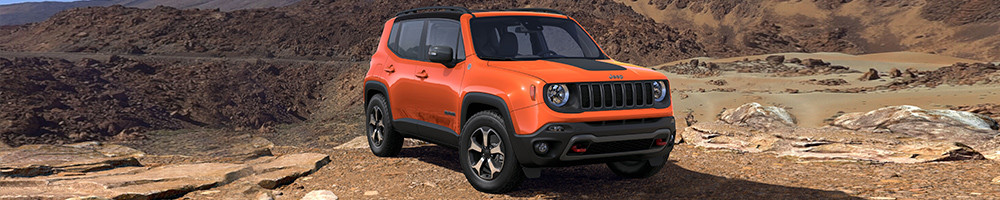 Jeep Renegade rouge garé sur un terrain rocailleux.
