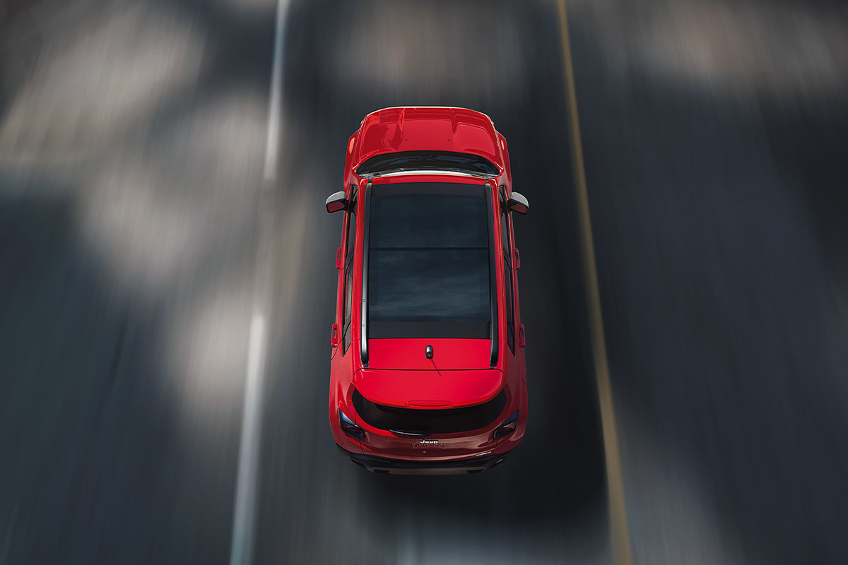 Aerial shot of a red Jeep Renegade driving on a road.