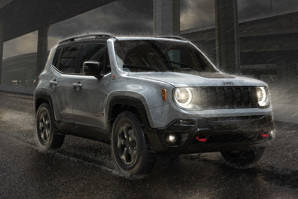 White Jeep Renegade being driven on a highway under the rain with the LED lights on.