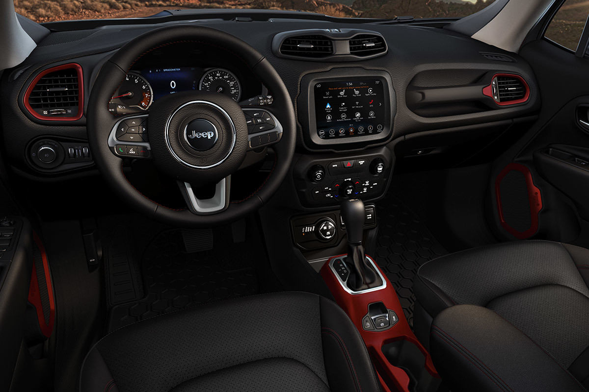 Interior shot of the Jeep Renegade from the driver’s seat perspective, showing the steering wheel, controls, and red bezels.