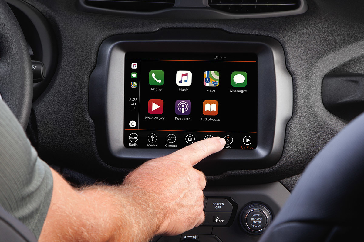 Driver sits in a Jeep Renegade and touches the entertainment system screen to select ‘Navigation.’
