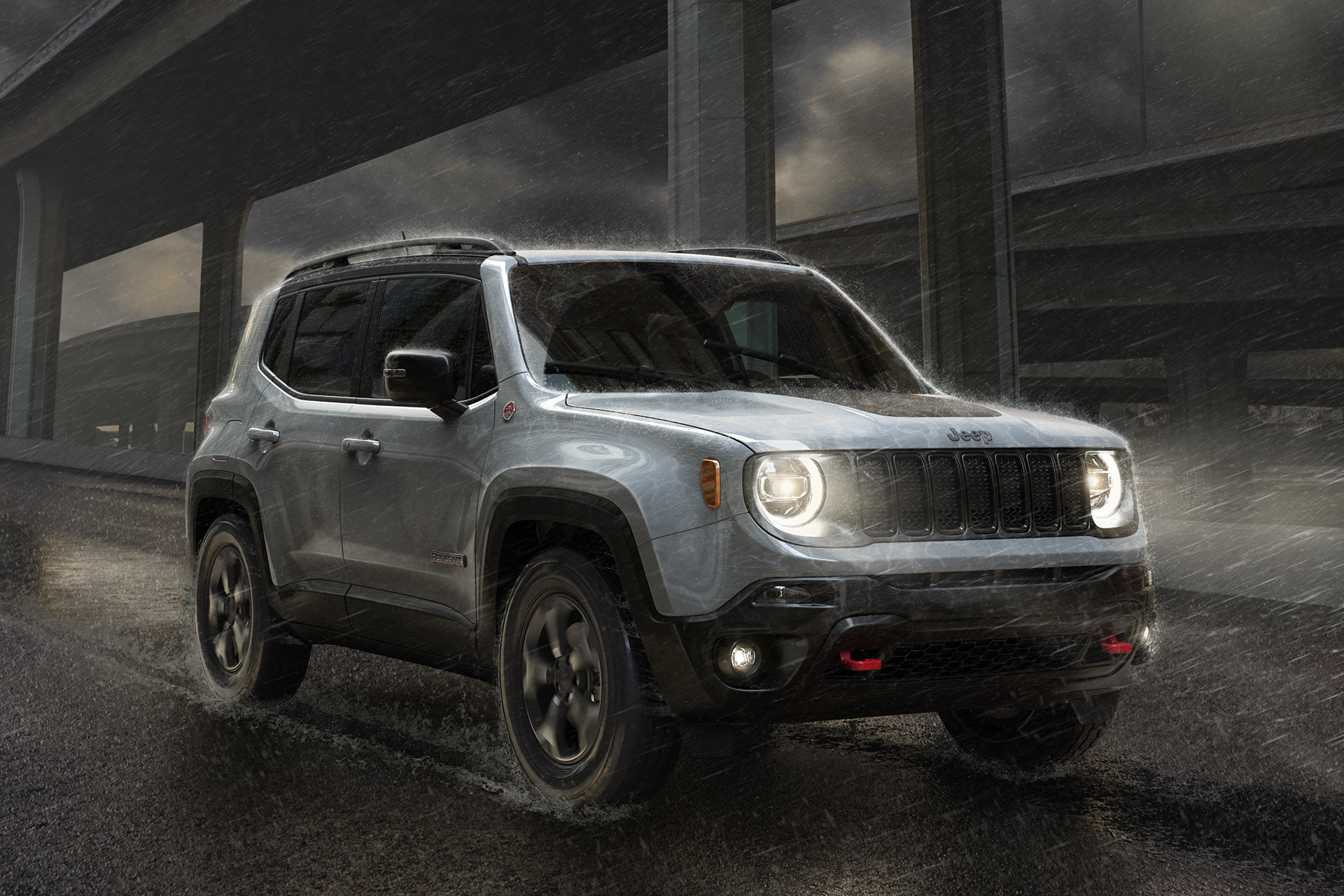 Jeep Renegade argent roulant sur l’autoroute près d’un pont alors que la pluie tombe.
