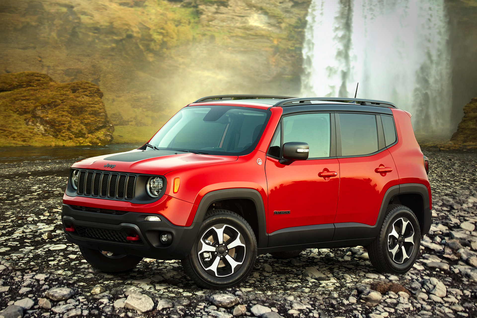 Red Jeep Renegade parked on a rocky shore near a waterfall and stream.