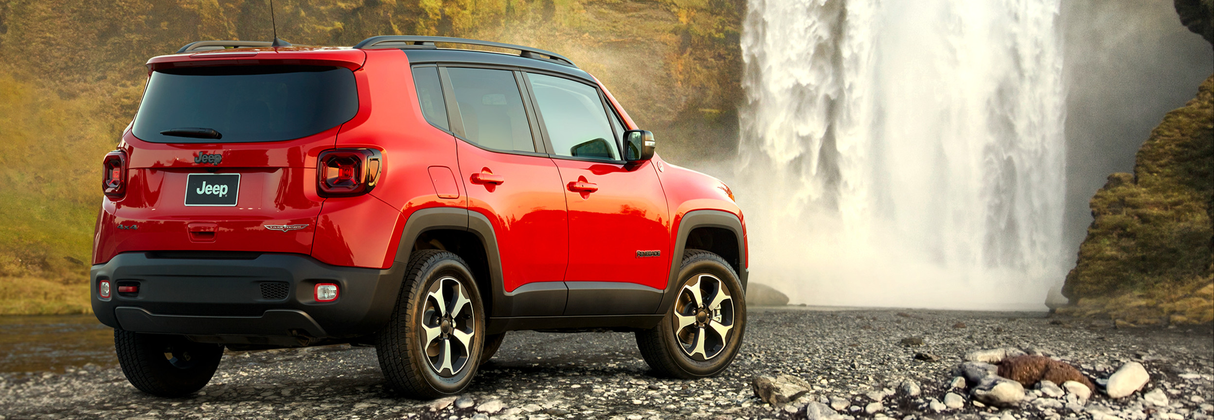 Extérieur d'une Jeep Renegade 2022 rouge garée devant une cascade.
