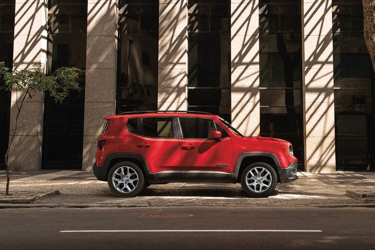 Profil latéral d’un Jeep Renegade 2022 rouge stationné dans une rue ensoleillée de la ville.