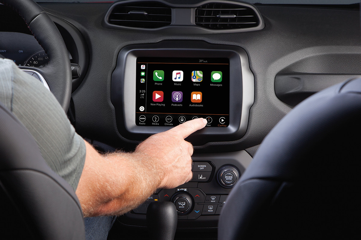 Habitacle du Renegade 2022 en noir vu de l’arrière avec le conducteur touchant le menu de l’écran Uconnect.