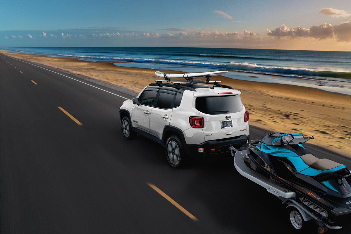 Jeep Renegade 2022 blanc tirant une motomarine sur une plage.