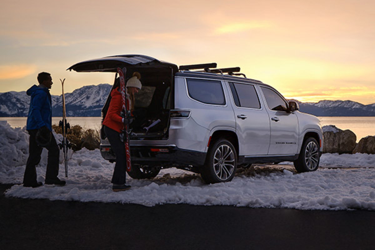 Vue de devant d’un Grand Wagoneer 2022 blanc, roulant sur une route dans la forêt