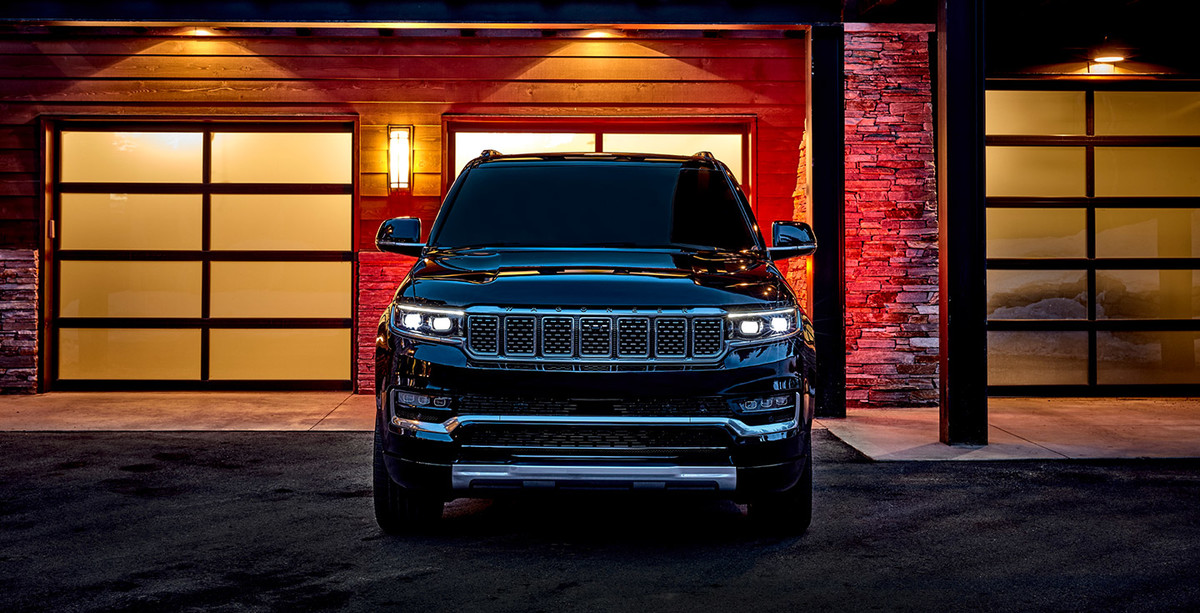 Front view of a black 2022 Grand Wagoneer parked in front of a house at night