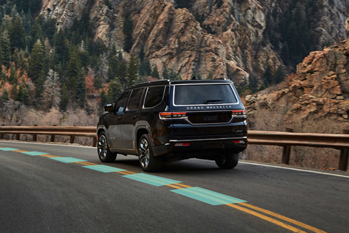 Rear view of a black 2022 Grand Wagoneer driving on a mountain road